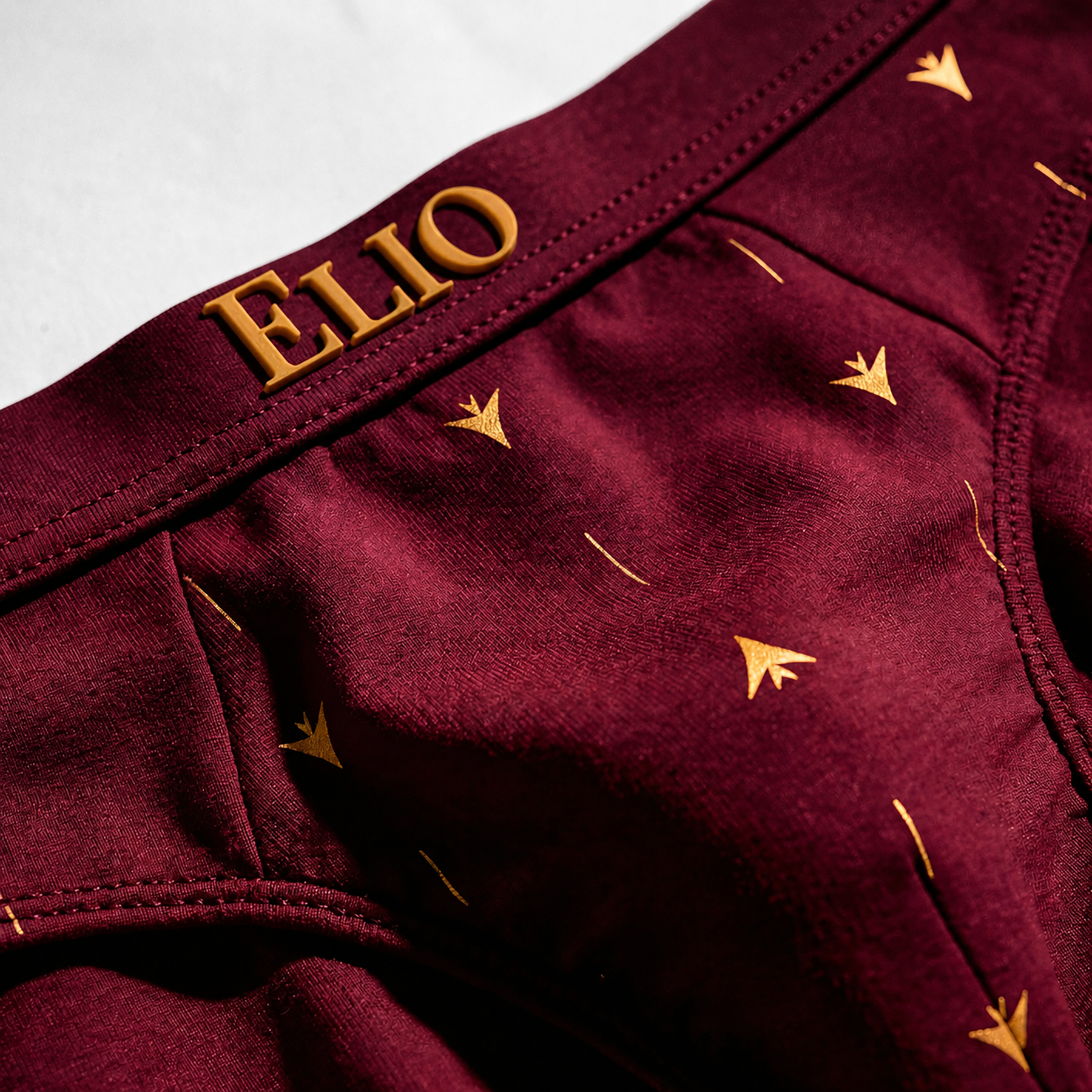ELIO brief with gold 'ELIO' branding and star patterns on a light gray background